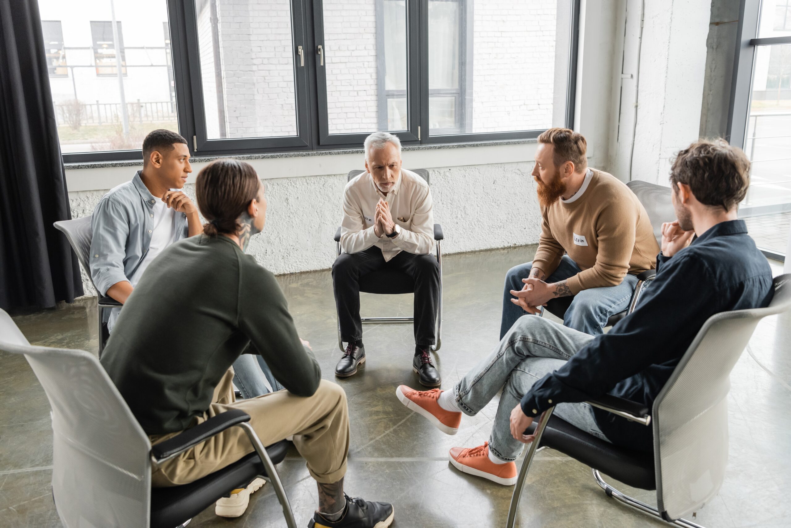 A diverse group of five people sit in a circle during a discussion