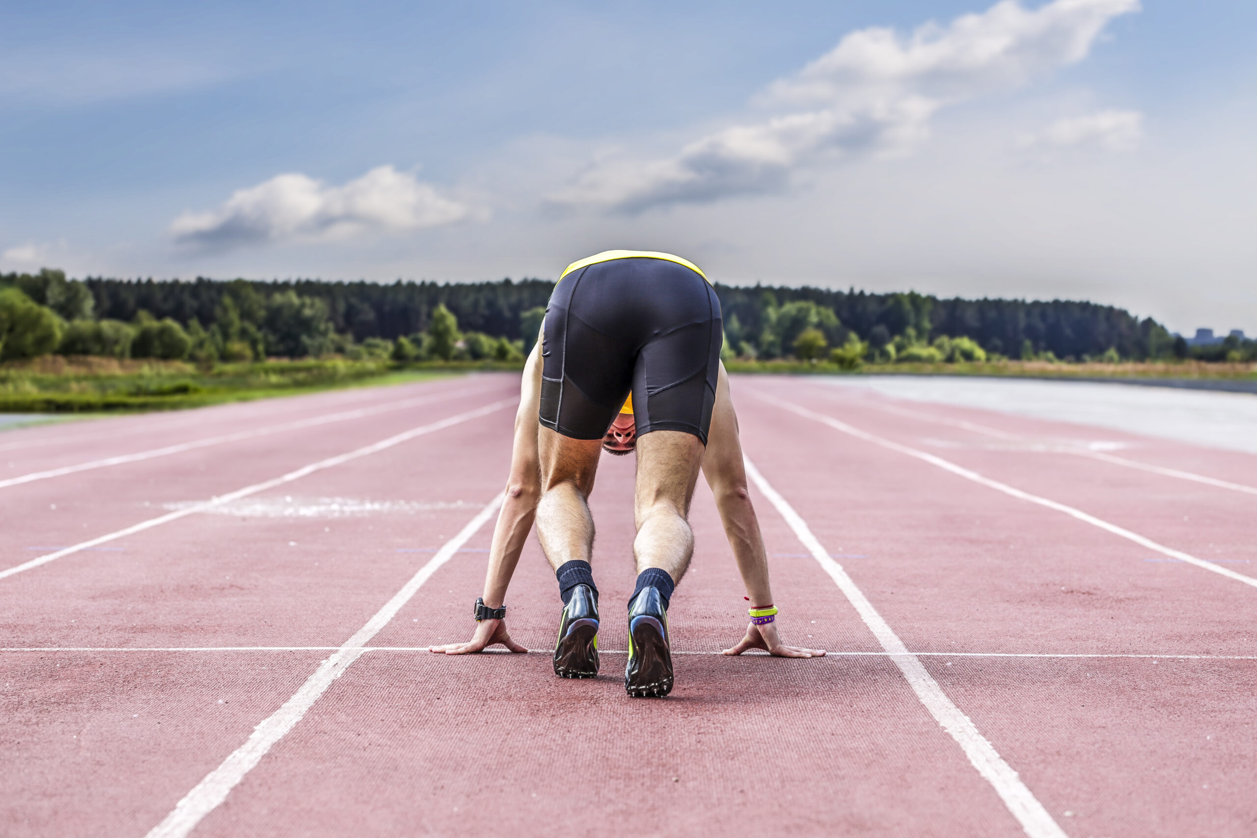 Athlete in a starting position on a track, preparing for a sprint.